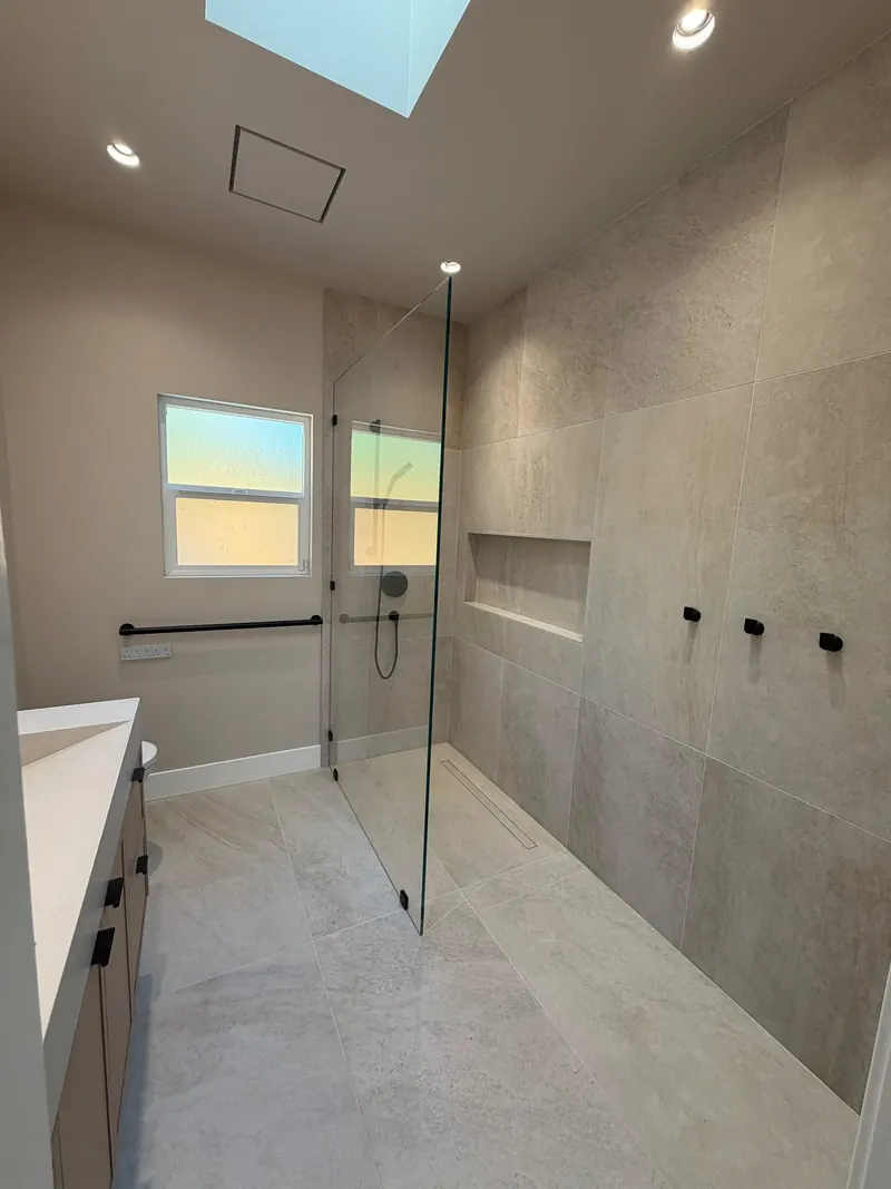 Walk-in shower with large-format stone-look tile, a fixed glass panel, a recessed niche and a linear drain