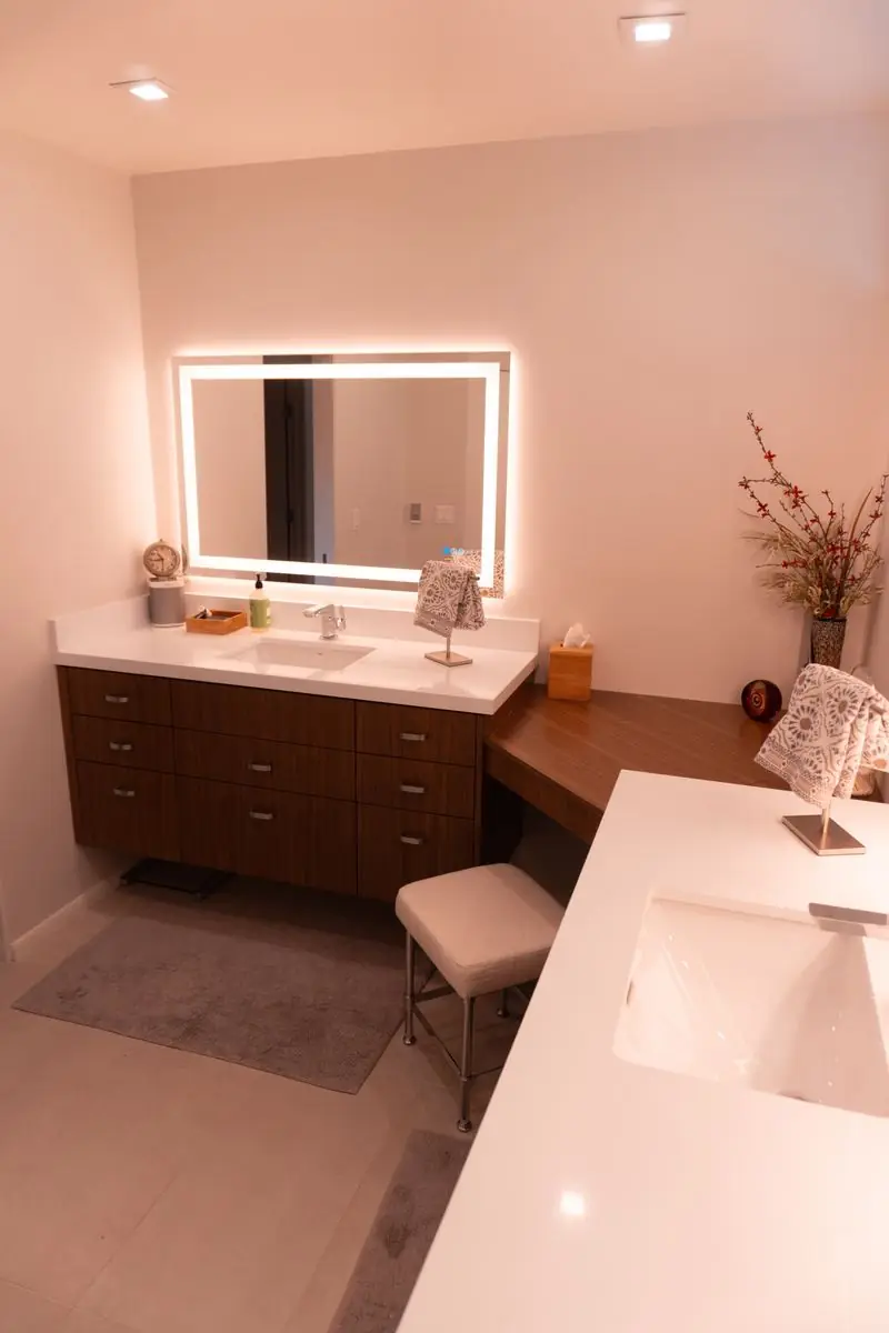 Backlit mirror above a walnut vanity