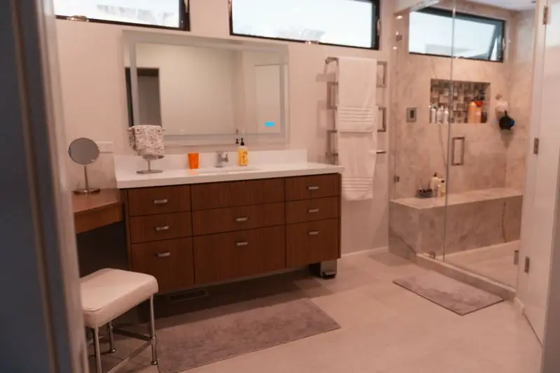 Primary bathroom with walnut vanity and glass shower enclosure