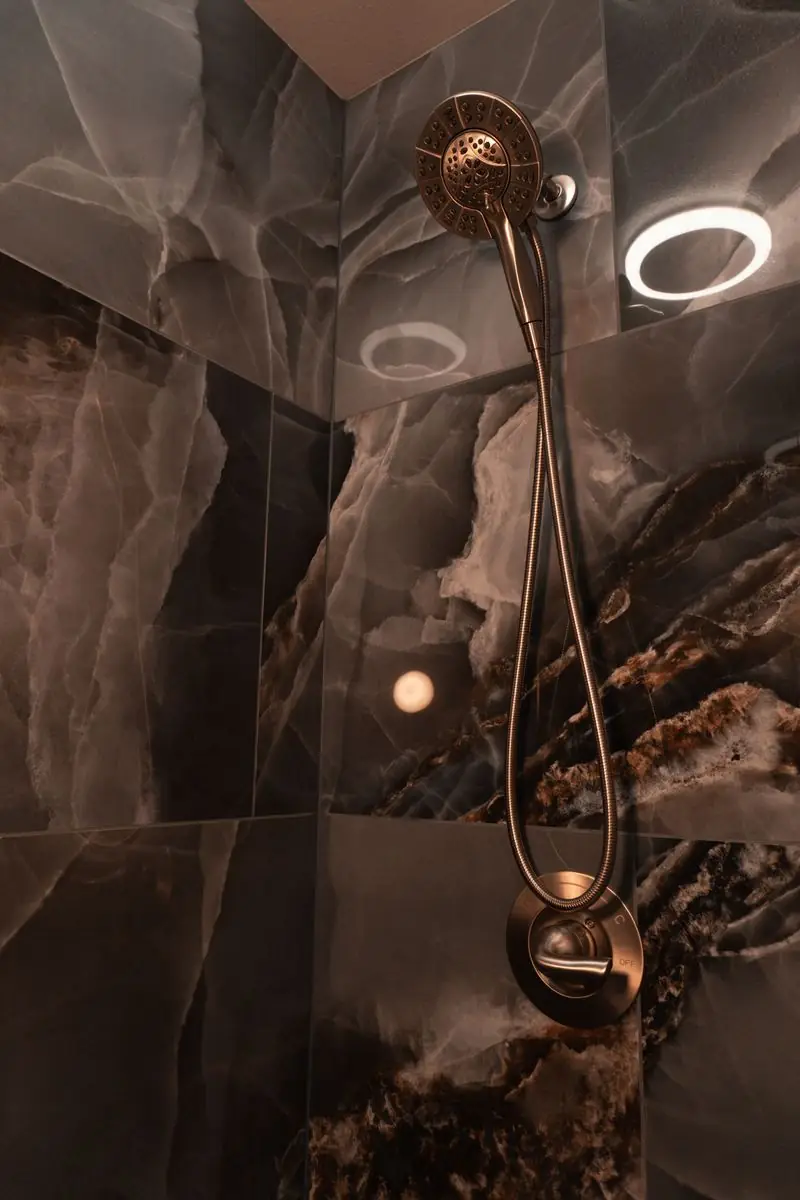 Shower clad in dark onyx-look porcelain with bronze fixtures